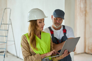 Fototapeta premium Manager holds open laptop and shows it to builder