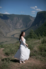 Bride in the mountains wedding image. A beautiful young woman in a wedding dress walks in the mountains.