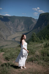 Naklejka premium Bride in the mountains wedding image. A beautiful young woman in a wedding dress walks in the mountains.