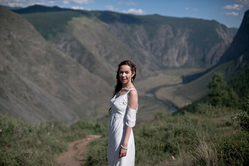Bride in the mountains wedding image. A beautiful young woman in a wedding dress walks in the mountains.