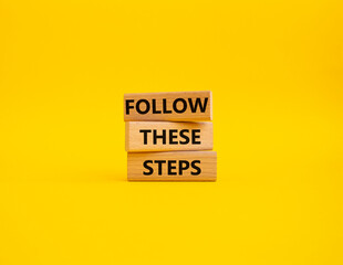 Follow these steps symbol. Wooden blocks with words Follow these steps. Beautiful yellow background. Business and Follow these steps concept. Copy space.