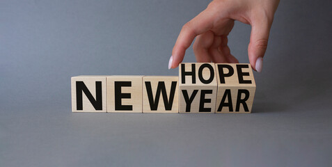 New year new hope symbol. Hand turns cubes and changes the words new year to new hope. Beautiful grey background. Businessman hand. Business concept. Copy space