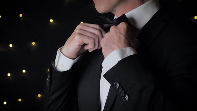 Close up view of man adjusts his bow tie.