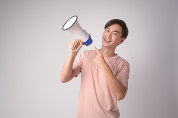 Young smiling man holding megaphone over white background studio..