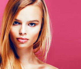 young pretty blonde real woman with hairstyle close up and makeup on pink background smiling