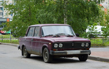 Old Soviet rusty burgundy car, Kollontai Street, St. Petersburg, Russia, August 2022