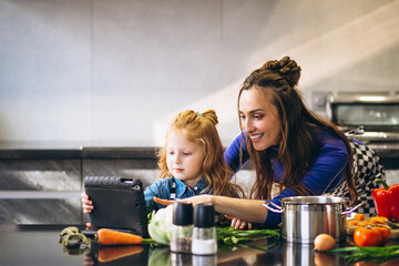 Mother and daughter with tablet cooking in kitchen