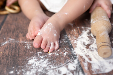 small children's feet in flour on a wooden background