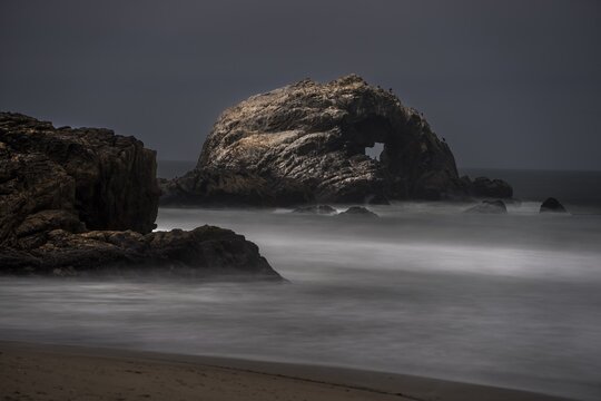 This image captures a moody ocean landscape with mist rolling in over the water.