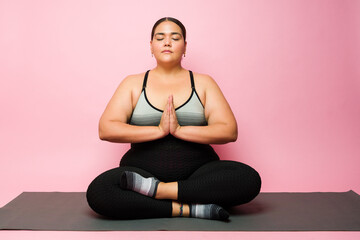 Obese latin woman relaxing and meditating during yoga exercises