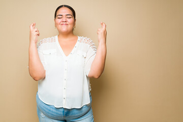 Plus size woman wishing for a miracle while crossing her fingers