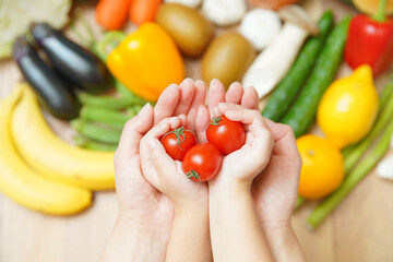 野菜の集合とプチトマトを持つ親子の手 