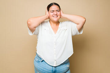Stressed overweight woman feeling overwhelmed with music or noise