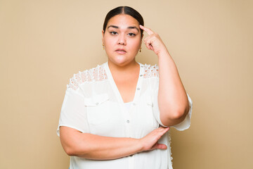 Thoughtful smart plus size woman making a thinking gesture