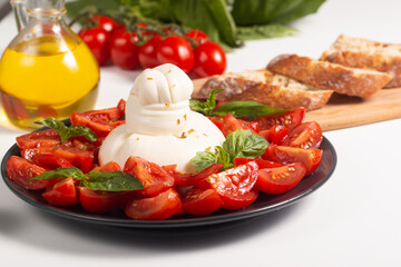 Traditional Italian burrata cheese with salad of delicious cherry tomato, basil leaves and olive oil