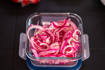Close-up of finely chopped, red and pickled onions in a glass bowl. Food in nature. Small depth of...