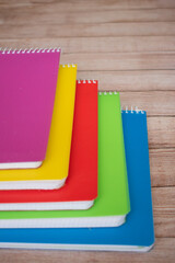 group of colored notebooks on a wooden table