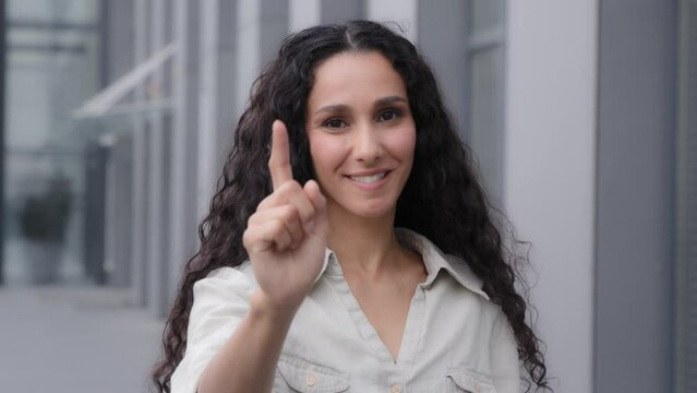 Head shot female millennial 30s woman with long curly hair pointing finger looking at camera making choice you are right gesture good idea sign with hand making offer support agree with forefinger
