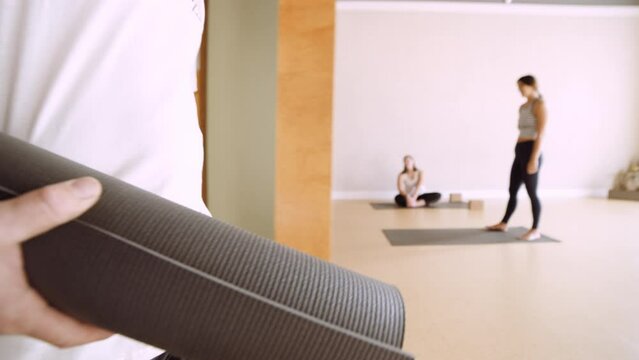Man carries yoga mat into yoga studio at start of class in slow motion
