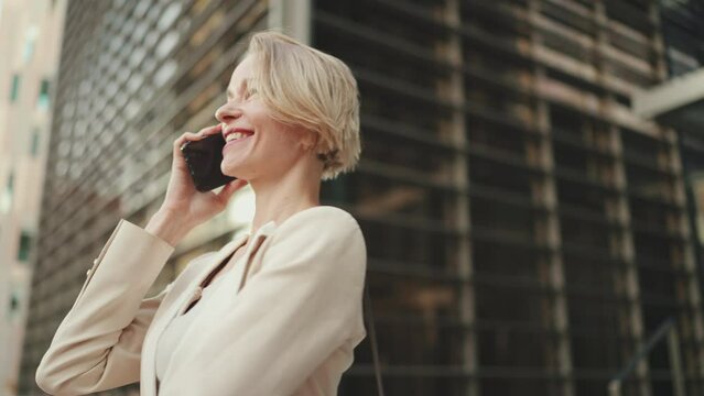 Happy businesswoman with blond hair talking on cellphone, good deal, success