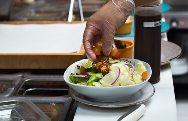 Kitchen employee preparing salad for customer food order