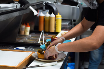 Fototapeta na wymiar Restaurant kitchen employee working on preparing customer food order