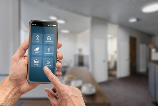 Man using mobile phone app for controlling smart home kitchen
