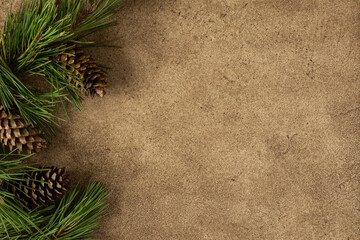 Christmas composition with pine branches and cones. Winter frame with forest trees on the brown background, horizontal. New year theme flat lay. Copy space