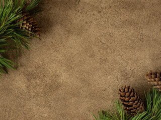 Christmas composition with pine branches and cones. Winter frame with forest trees on the brown background, horizontal. New year theme flat lay. Copy space