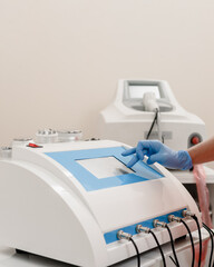 Young cosmetologist using modern machine for laser hair removal in beauty salon