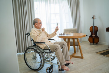 Senior man sitting on wheelchair and talking to relatives on video call conference in living...