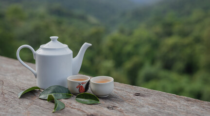 White ceramic teapot set on the table with natural mountain view in the morning.