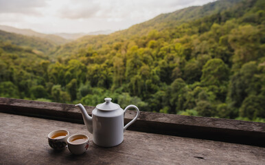 White ceramic teapot set on the table with natural mountain view in the morning.