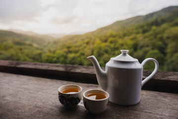White ceramic teapot set on the table with natural mountain view in the morning.