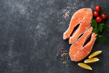 Salmon. Raw salmon steak. Fresh raw salmon fish with cooking ingredients, herbs and lemon prepared for grilled baking on black background. Healthy food. Top view. Copy space.
