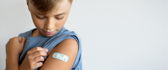 Child after vaccination with a adhesive band-aid patch arm bandage to prevent any infection over...