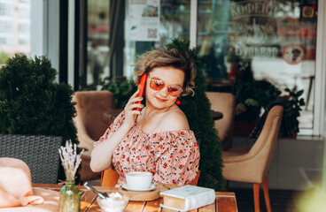A woman talking on the phone, A woman with a mobile phone is sitting in a cafe. a woman in a dress and a hat in a cafe