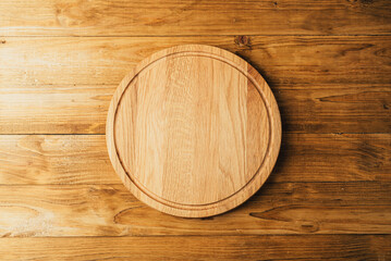Round cutting board for pizza on a wooden background.