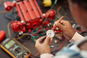 Close up of child building robot and wiring circuit board during engineering class at school, copy...