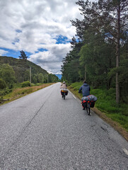 Fototapeta premium Two cycling male tourists moving on Norway fjords coastal road 4