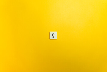 Cedilla Diacritical Mark on Letter Tile on Yellow Background. Minimal Aesthetics.