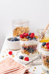 Granola with yogurt in glass served with fresh raspberry, blueberry and honey. Homemade oatmeal...