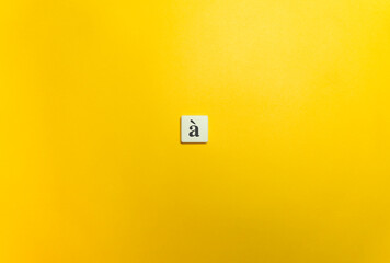 Grave Accent Diacritical Mark on Letter Tile on Yellow Background. Minimal Aesthetics.