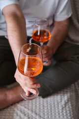 A glass of wine, aperol in the hands of a man resting at home Tasting alcoholic beverages. Romantic evening aperitif. Close-up of a glass of wine. Enjoy the moment