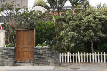 Puerta de madera color marrón junto a un cerco de piedras.