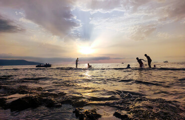 silhouettes of Group of young people swiming during the sunset. Beach holidays travel concept