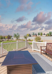 Vertical Puffy clouds at sunset Deck of a house with potted pine tree near the fire pit table an