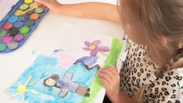 Talented Creative Child Girl Female Artist Draws with Her Hands on Paper, Using Fingers Paints Brush Creates Colorful, Kid Drawing on table at Home. Painter Creating Abstract Modern Art. Childhood