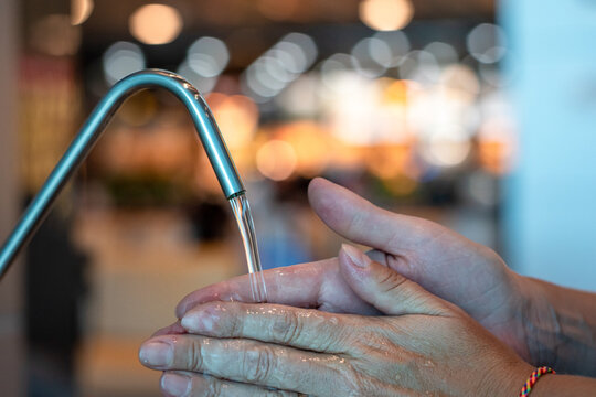 Persona lavandose las manos en terminal de higiene de un aeropuerto. Fotografía con enfoque selectivo