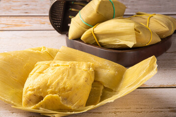 Pamonha, corn-based Brazilian food, arranged on a rustic wooden table, selective focus.